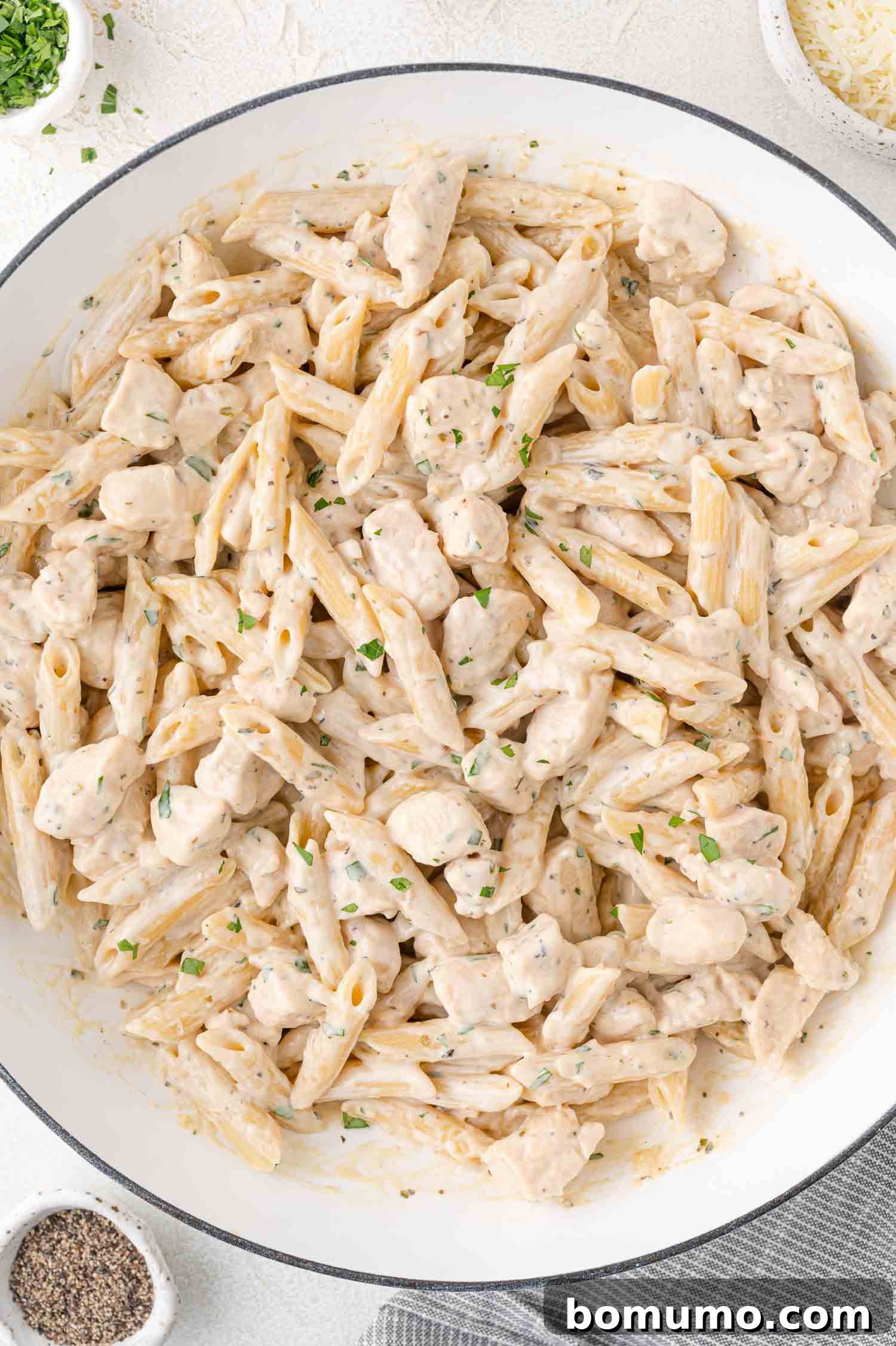 Creamy Chicken Skillet Pasta 3 A beautifully presented close-up of a creamy pasta dish featuring penne and generous chunks of perfectly cooked chicken, elegantly garnished with fresh herbs, served invitingly in a pristine white bowl, showcasing its rich texture.