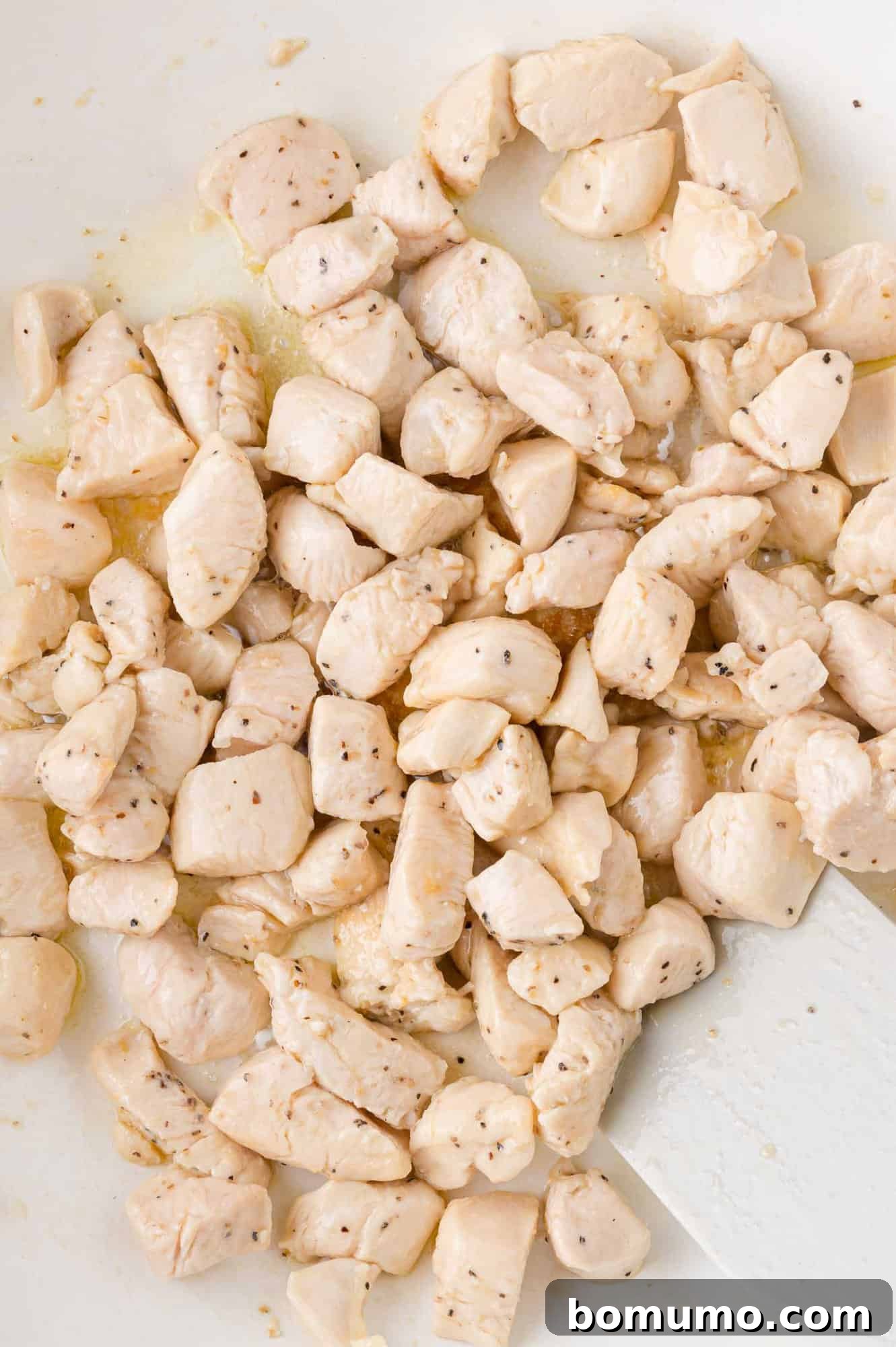 Creamy Chicken Skillet Pasta 6 Perfectly cooked and seasoned chicken pieces, golden-brown and tender, resting on a clean white surface after being expertly seared in the pan, awaiting reintroduction.