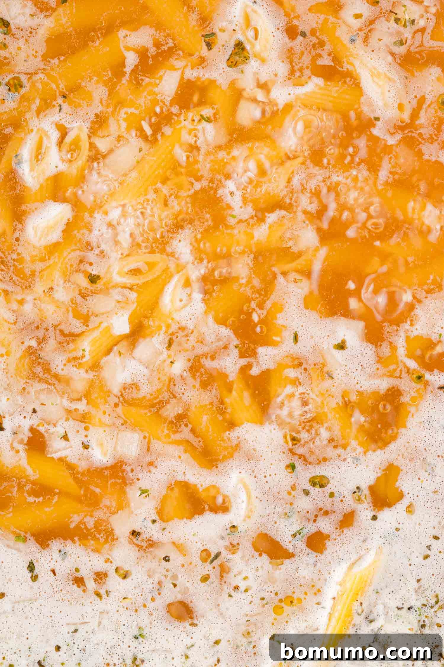 Creamy Chicken Skillet Pasta 10 Penne pasta vigorously boiling in a savory broth, with visible herbs and active bubbling liquid, indicating it's cooking perfectly and absorbing the rich flavors.