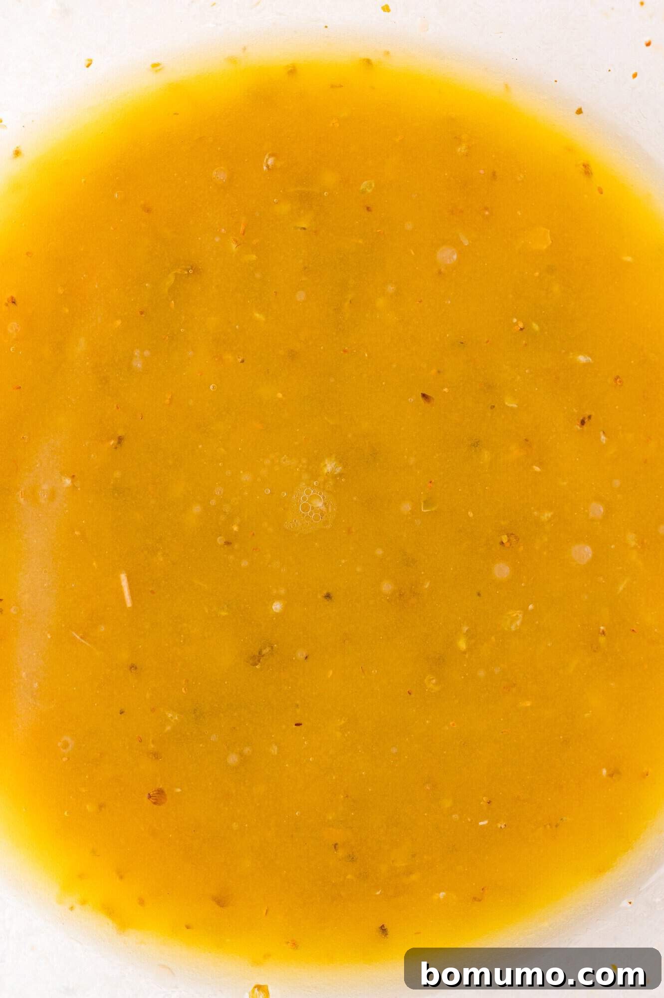 A close-up view of a bowl filled with orange-yellow salad dressing.