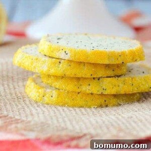 Front view of four poppy seed cookies stacked on burlap cloth.