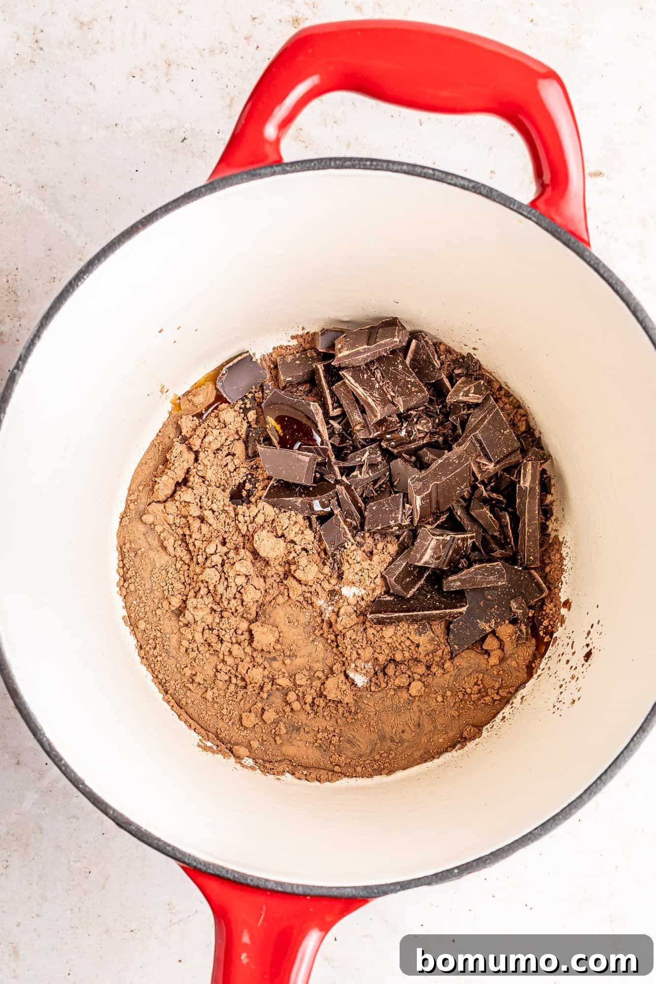 Dry ingredients like cocoa powder and chopped dark chocolate in a small saucepan, ready for liquid.