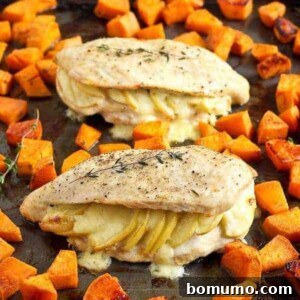 Two stuffed chicken breasts on sheet pan with sweet potatoes.