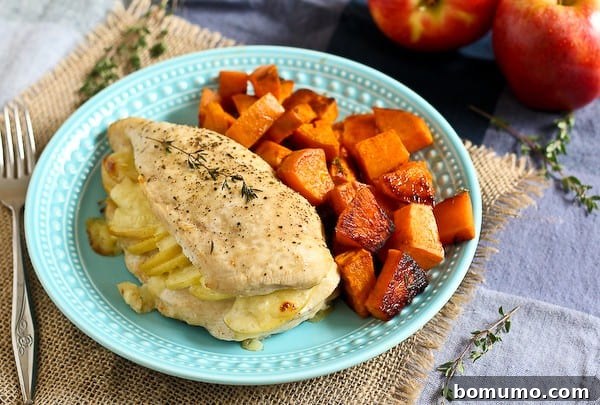A beautifully plated dinner featuring a stuffed chicken breast and roasted sweet potatoes on a decorative blue plate, garnished with fresh thyme.
