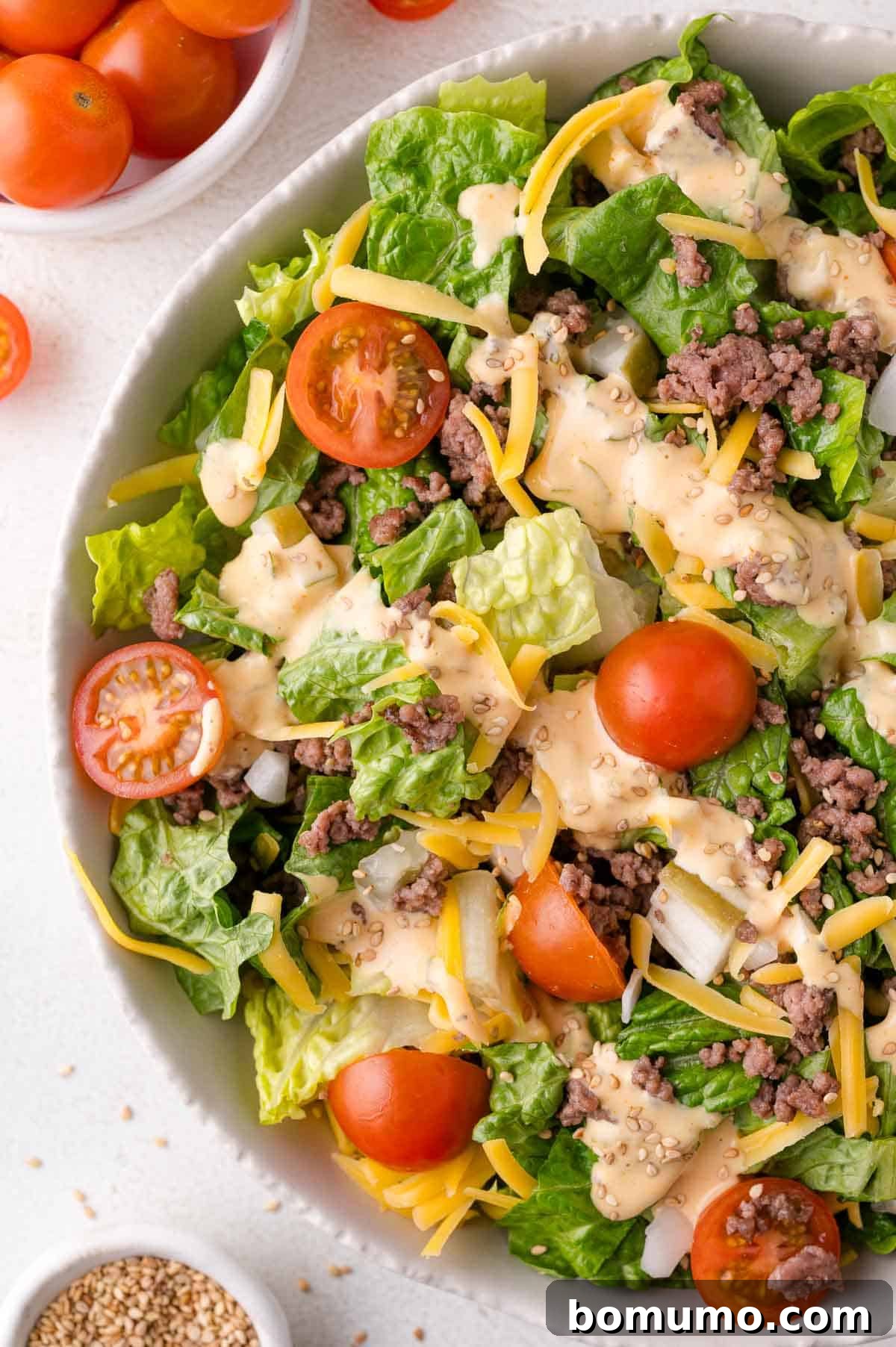 Classic Cheeseburger Salad 9 A well-mixed Big Mac Salad in a bowl, showing combined lettuce, ground beef, cherry tomatoes, shredded cheese, and a generous coating of creamy dressing, ready to be served.