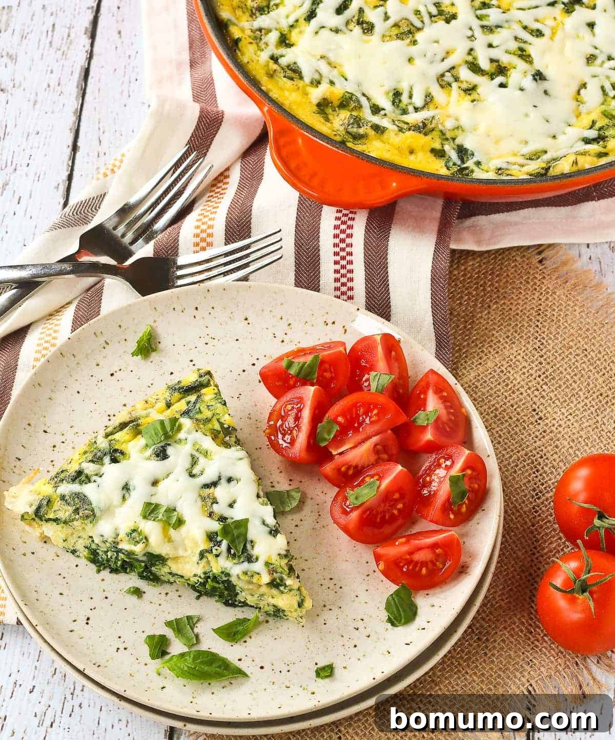 A perfectly portioned slice of White Pizza Frittata on a plate, garnished with fresh tomatoes, ready to be enjoyed.
