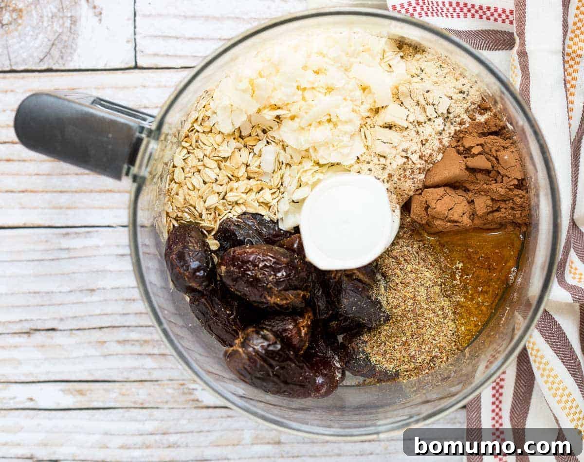 Wholesome ingredients like dates, oats, cocoa, and flaxseed meal in a food processor, ready to be blended for nut-free energy balls.