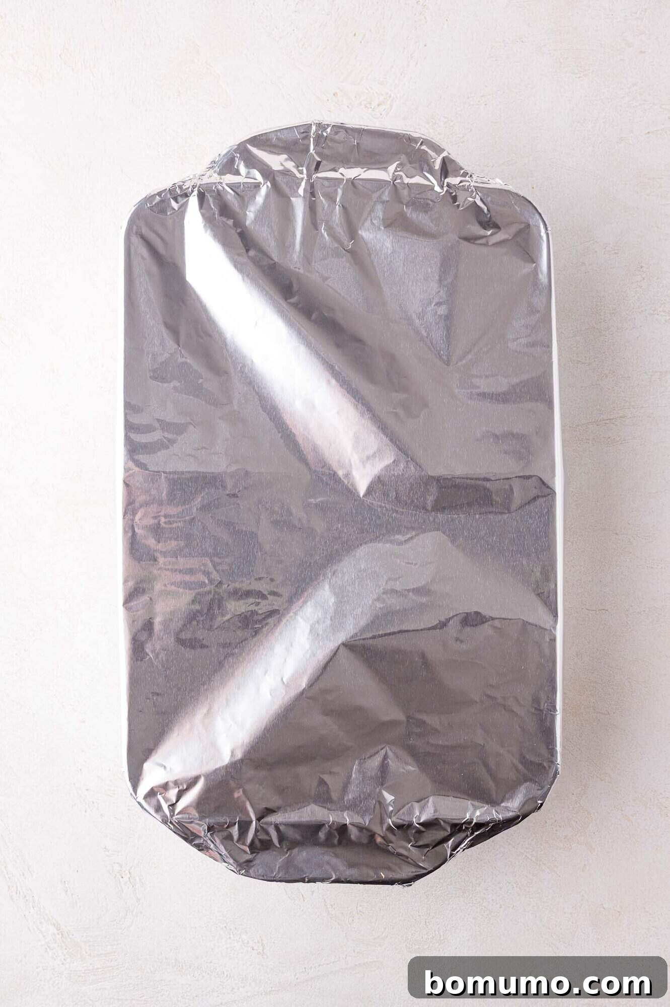 Hearty Beef Enchilada Bake 13 Rectangular baking dish covered with aluminum foil, placed on a light-colored surface.