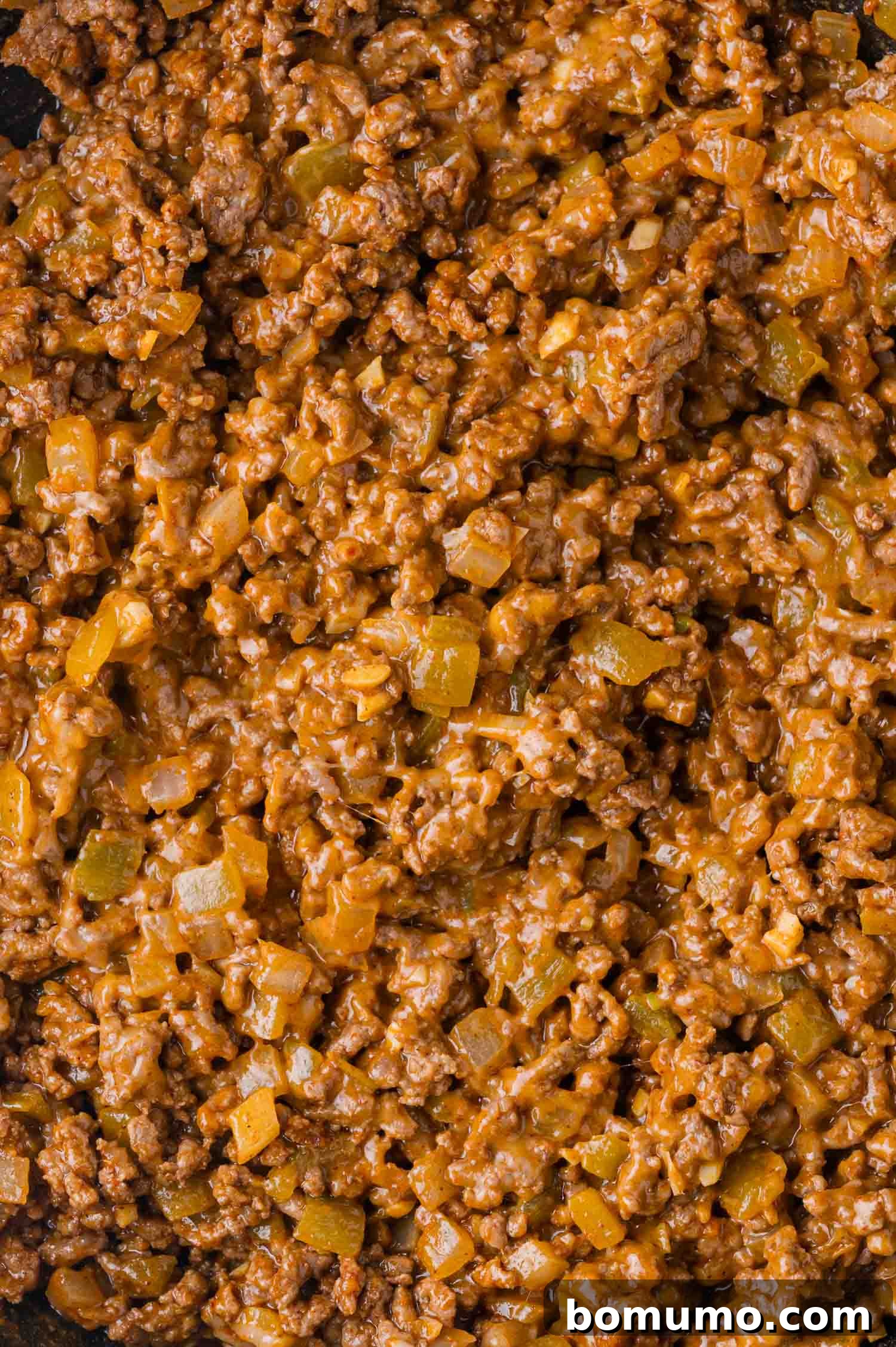 Hearty Beef Enchilada Bake 9 Close-up of browned ground beef mixed with diced onions and peppers, all coated in a rich, brown sauce.