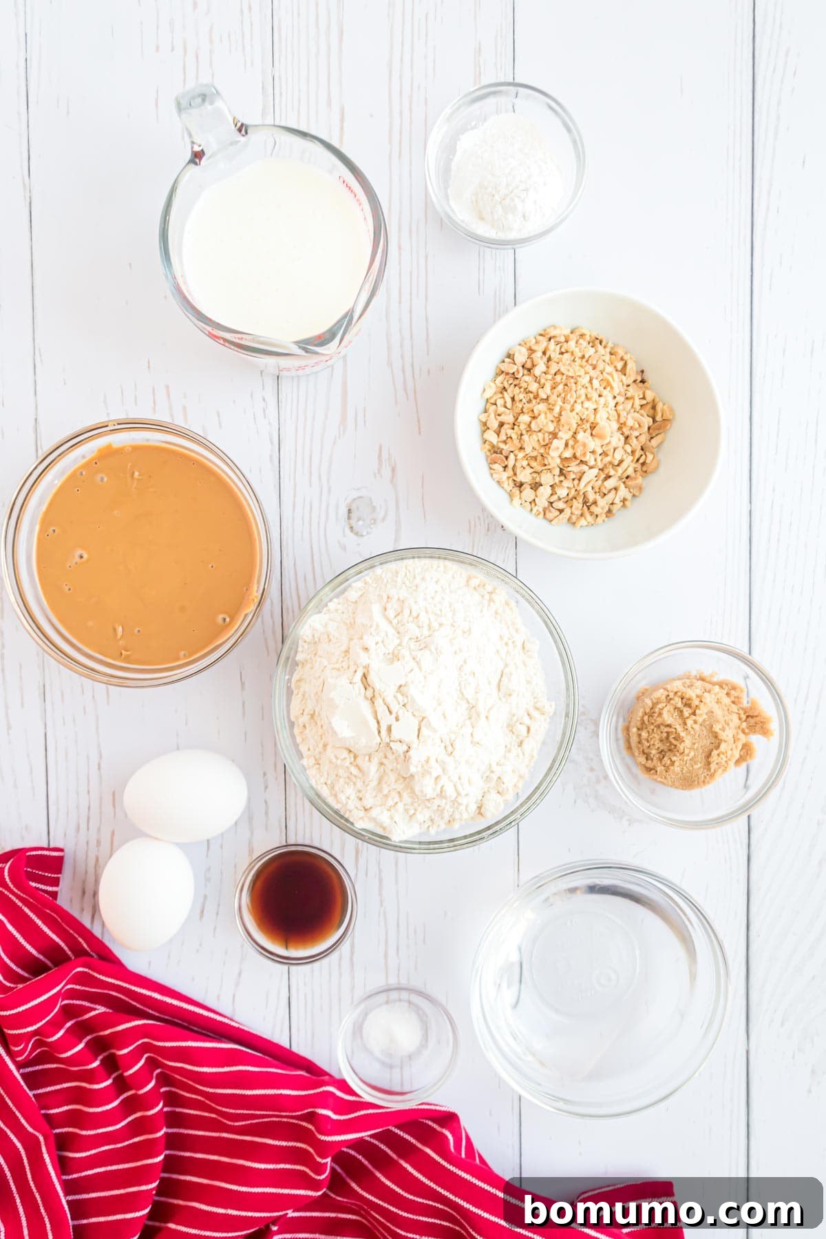 A curated collection of fresh ingredients displayed in elegant white bowls on a pristine white surface, including rich peanut butter, golden-brown sugar, and finely chopped nuts, ready for an exciting cooking adventure.