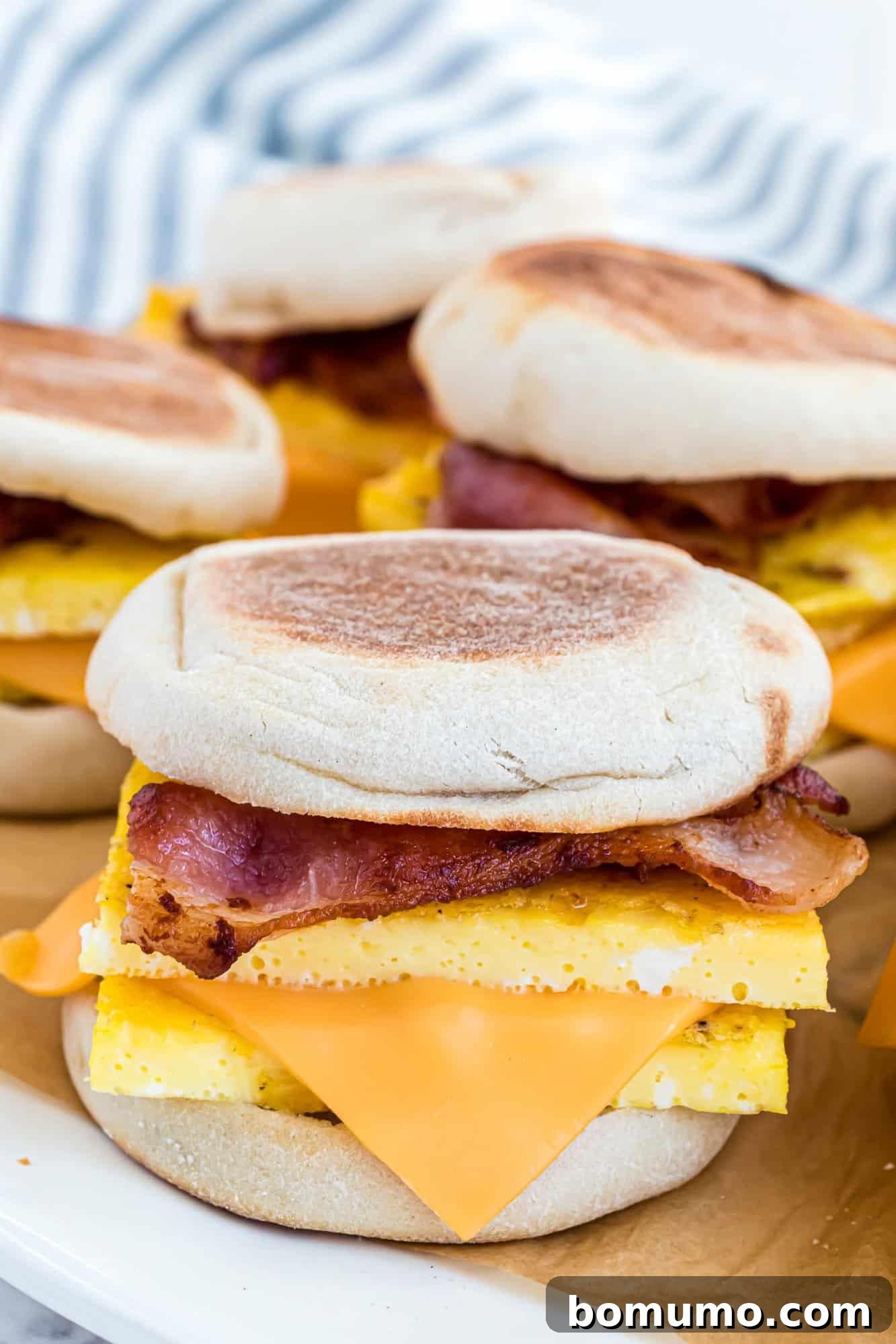 Breakfast Sandwich Bliss 13 Breakfast sandwiches with English muffins, bacon, egg, and cheese stacked on a plate.