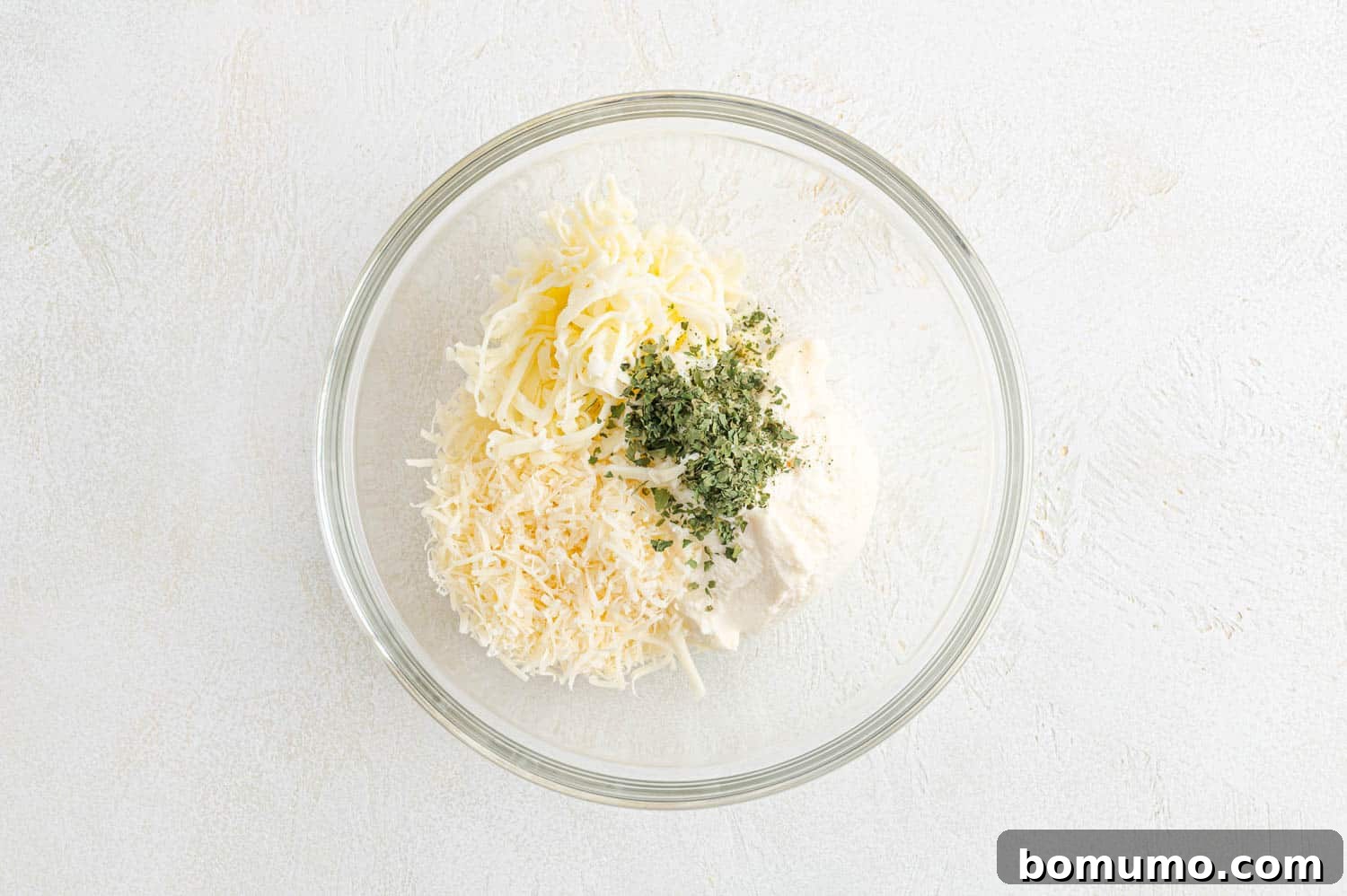 Individual cheeses (ricotta, Parmesan, mozzarella) arranged in a bowl before mixing for the topping.