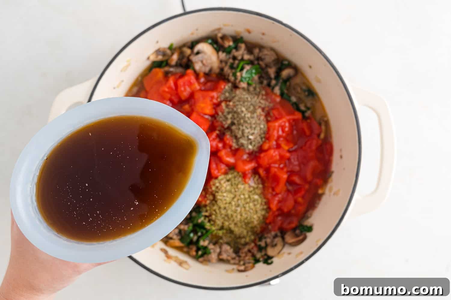 Beef broth being poured into the pan, forming the liquid base of the lasagna soup.