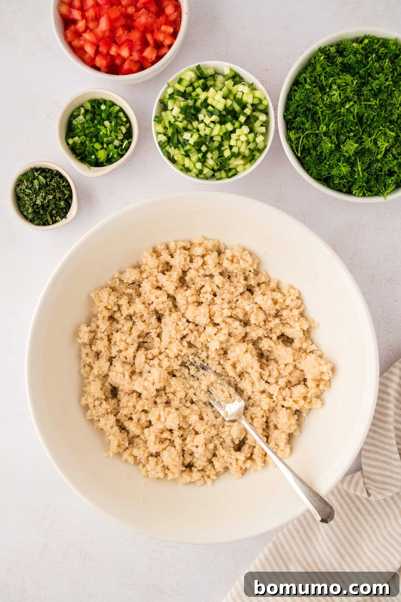Fluffy, cooked bulgur wheat resting in a pristine white bowl, ready for the next steps in making tabbouleh.