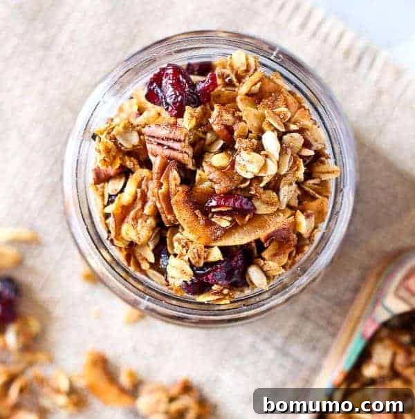 Overhead view of granola in a jar, with cranberries and pecans.