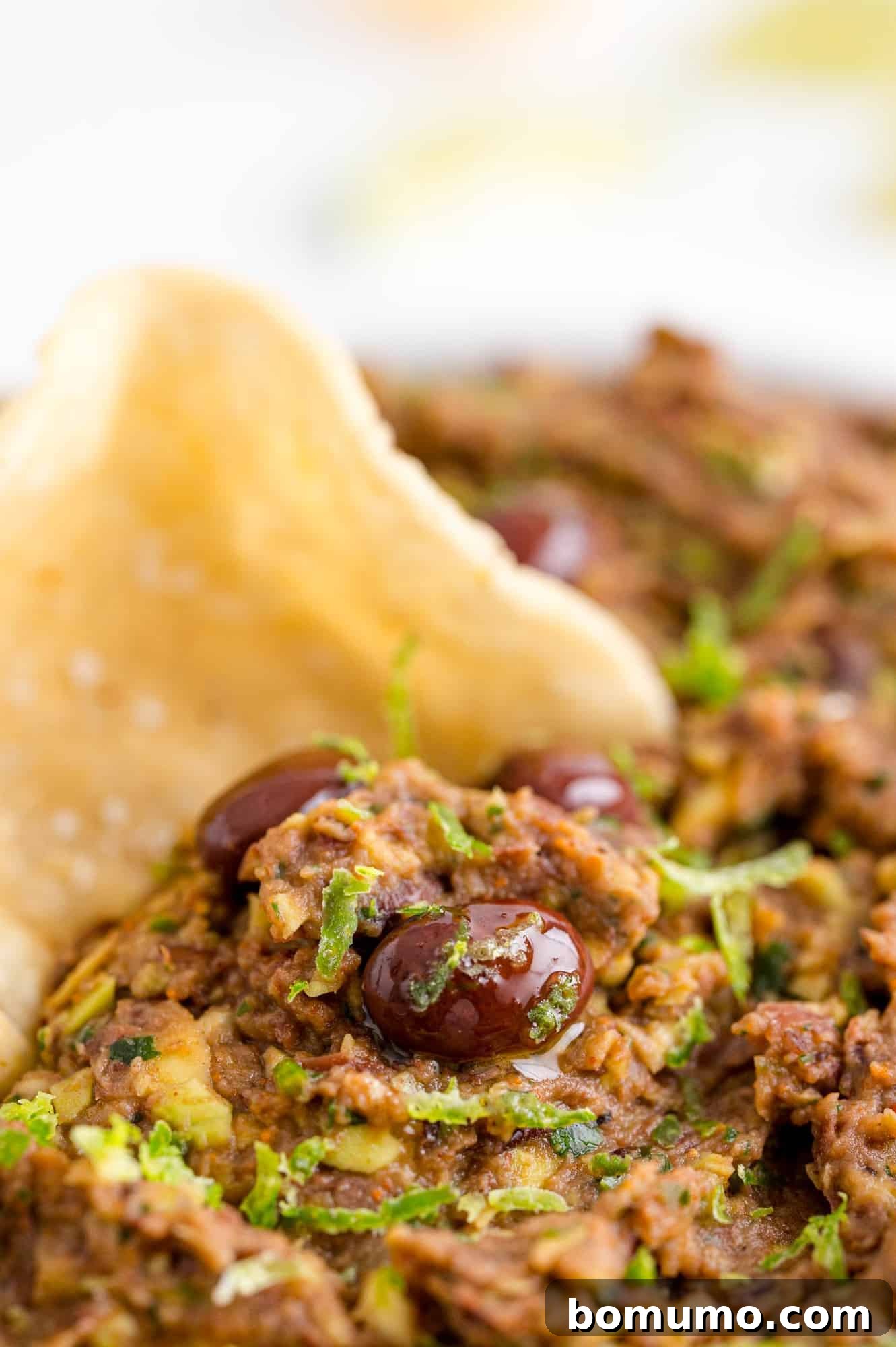 Crispy chip being dipped into a rich and creamy black bean dip, highlighting its perfect texture and vibrant appeal.
