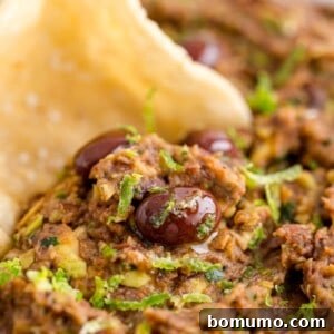 Black bean dip with a chip being dipped in it, highlighting its texture and inviting presentation.
