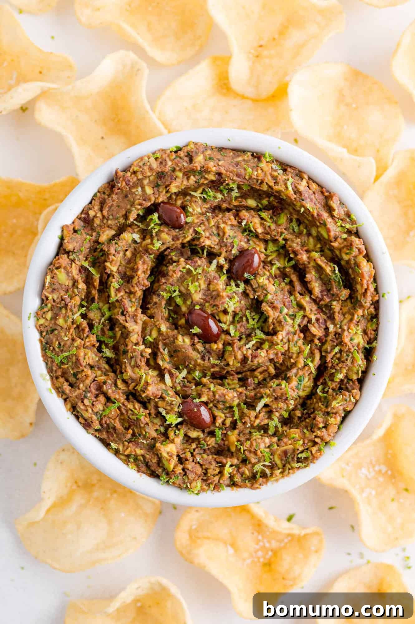 An inviting overhead shot of creamy black bean dip surrounded by crispy tortilla chips, ready for dipping.