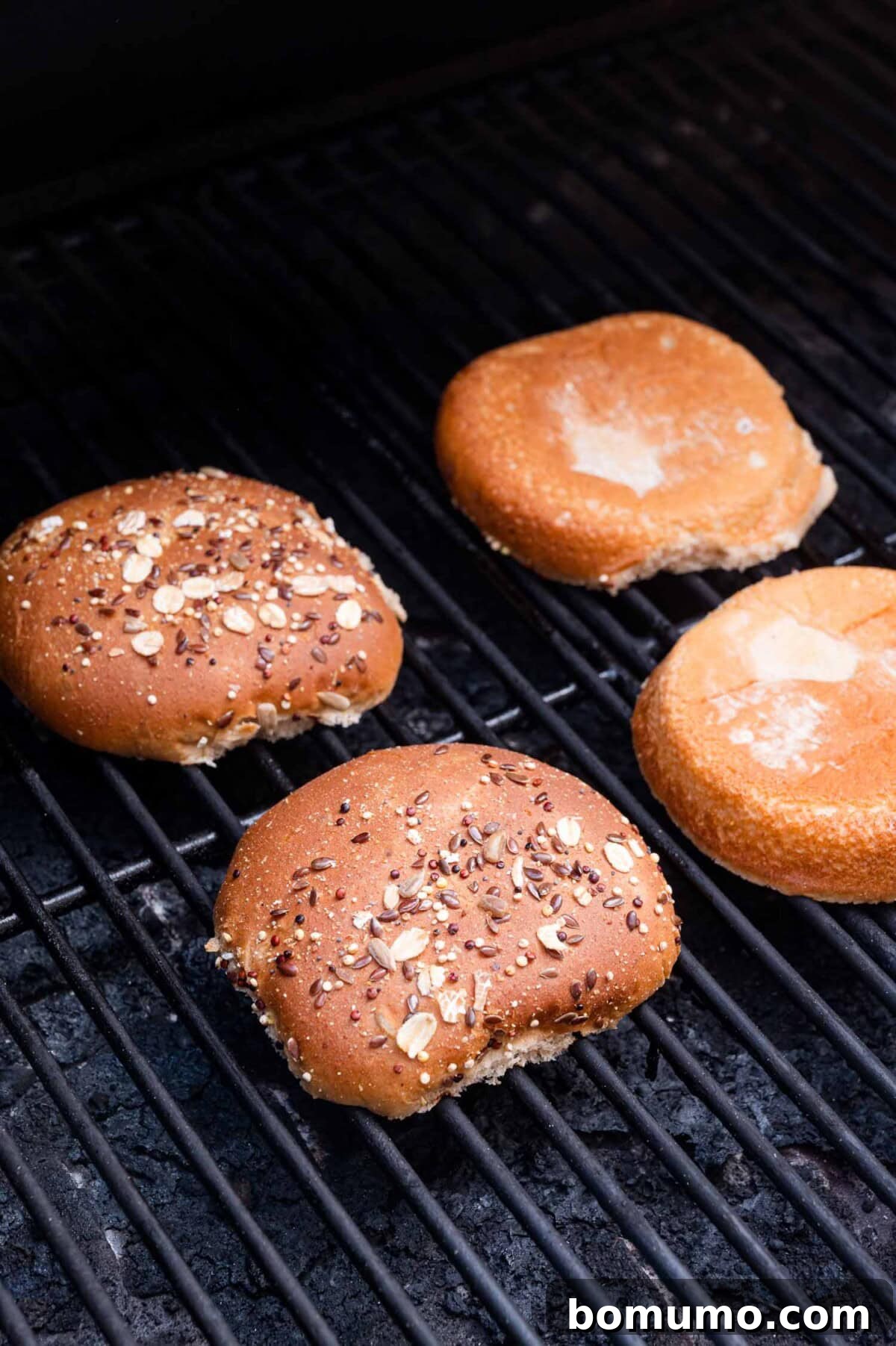 Two hamburger buns achieving a perfect golden toast on a hot grill, adding essential texture to the sandwich.