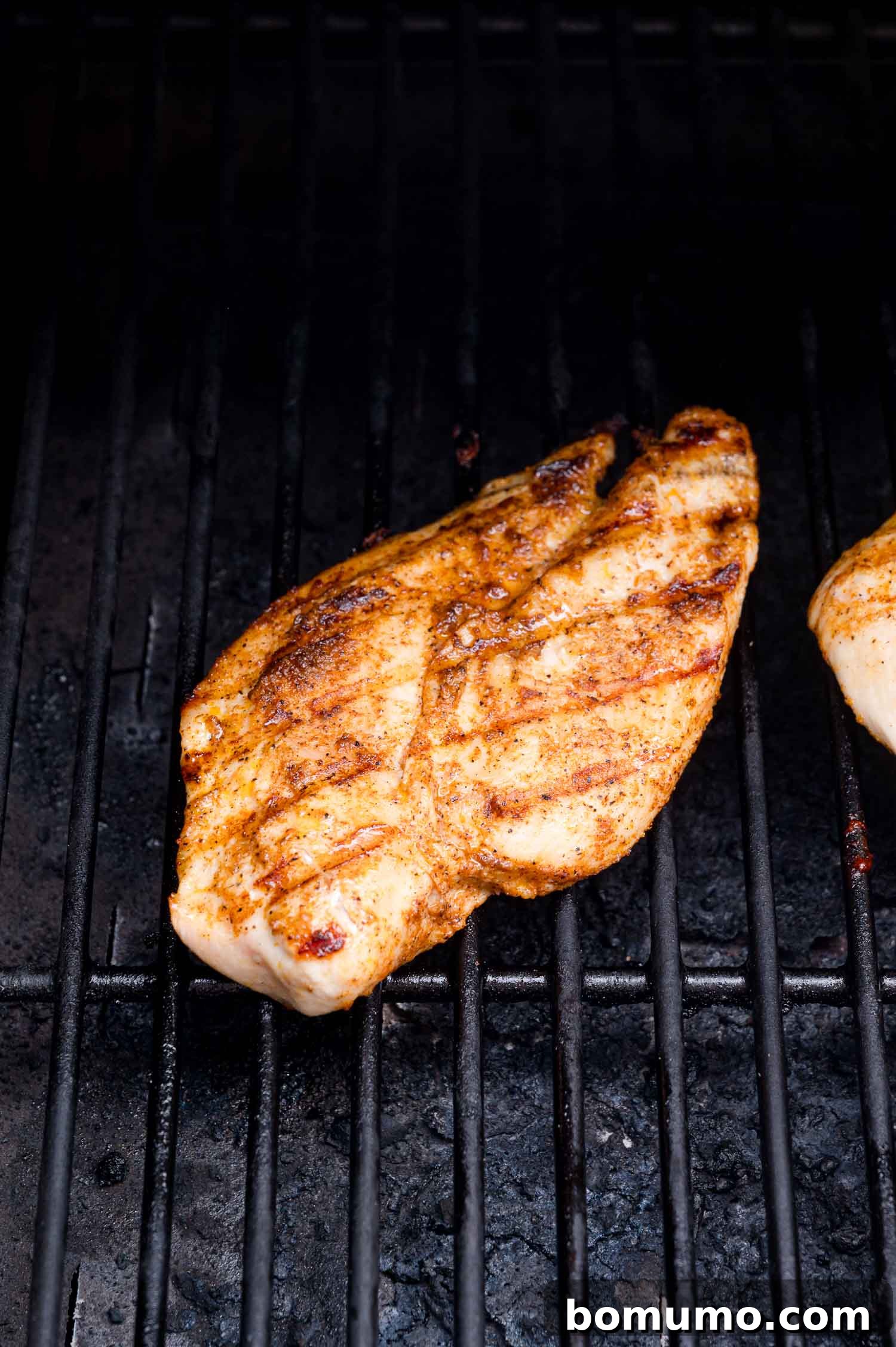 A seasoned chicken breast sizzling on a hot grill, displaying appealing grill marks and subtle char, indicating perfect cooking.