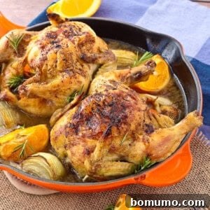 Two cornish game hens in a orange skillet.