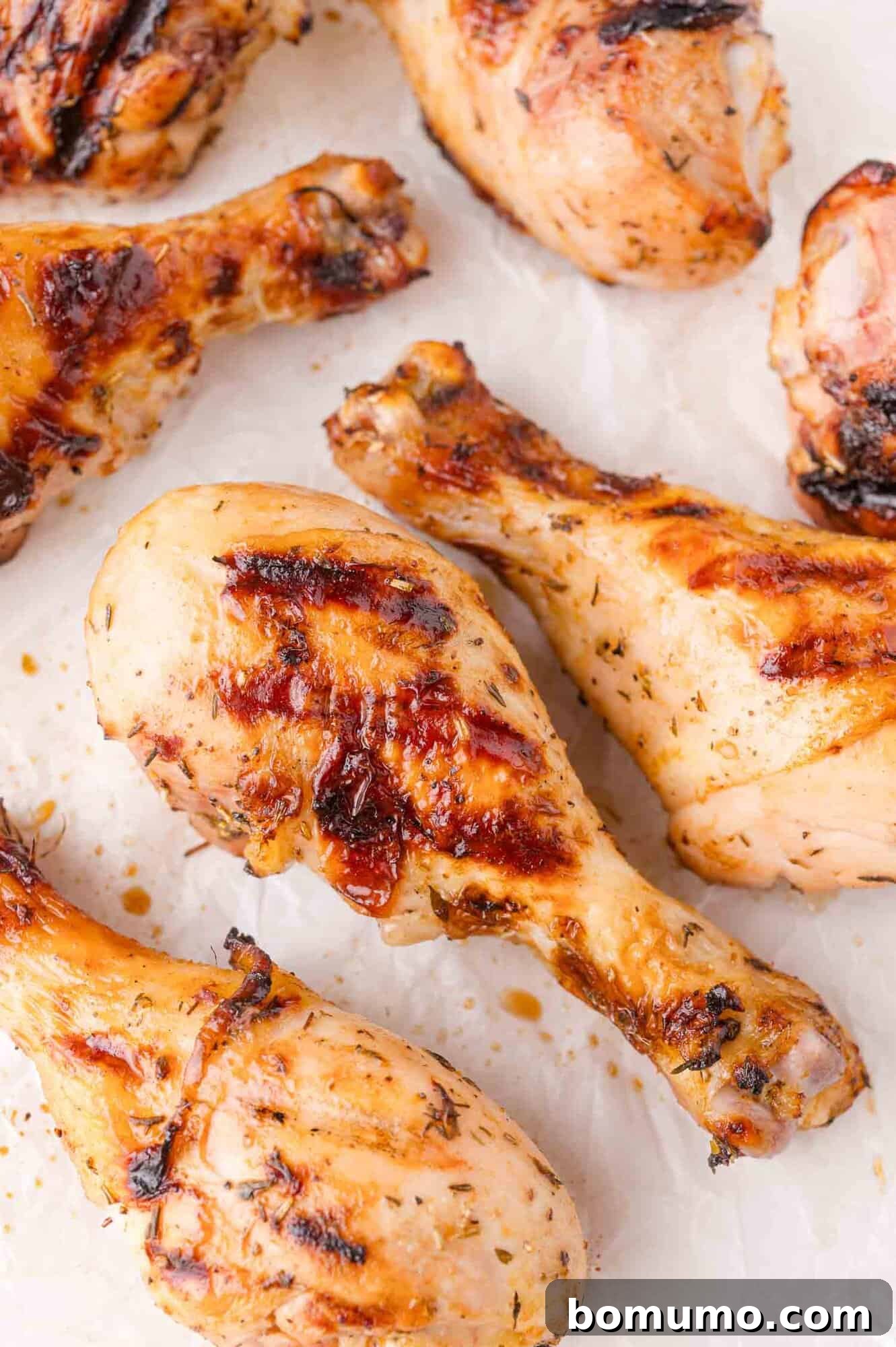 Grilled chicken drumsticks with charred grill marks, arranged on a white surface, ready to be served.
