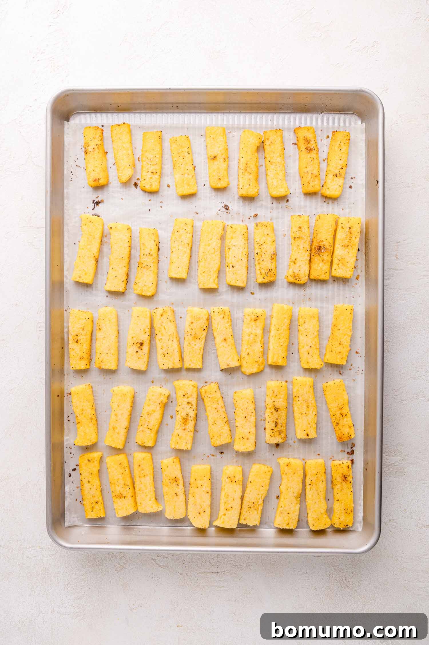 Seasoned polenta fries on a baking sheet.