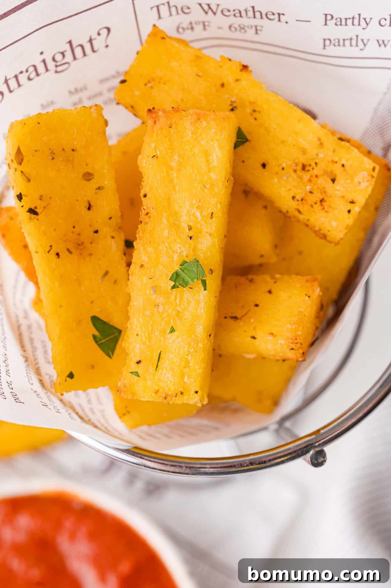 Crispy polenta fries in a basket with dipping sauce.