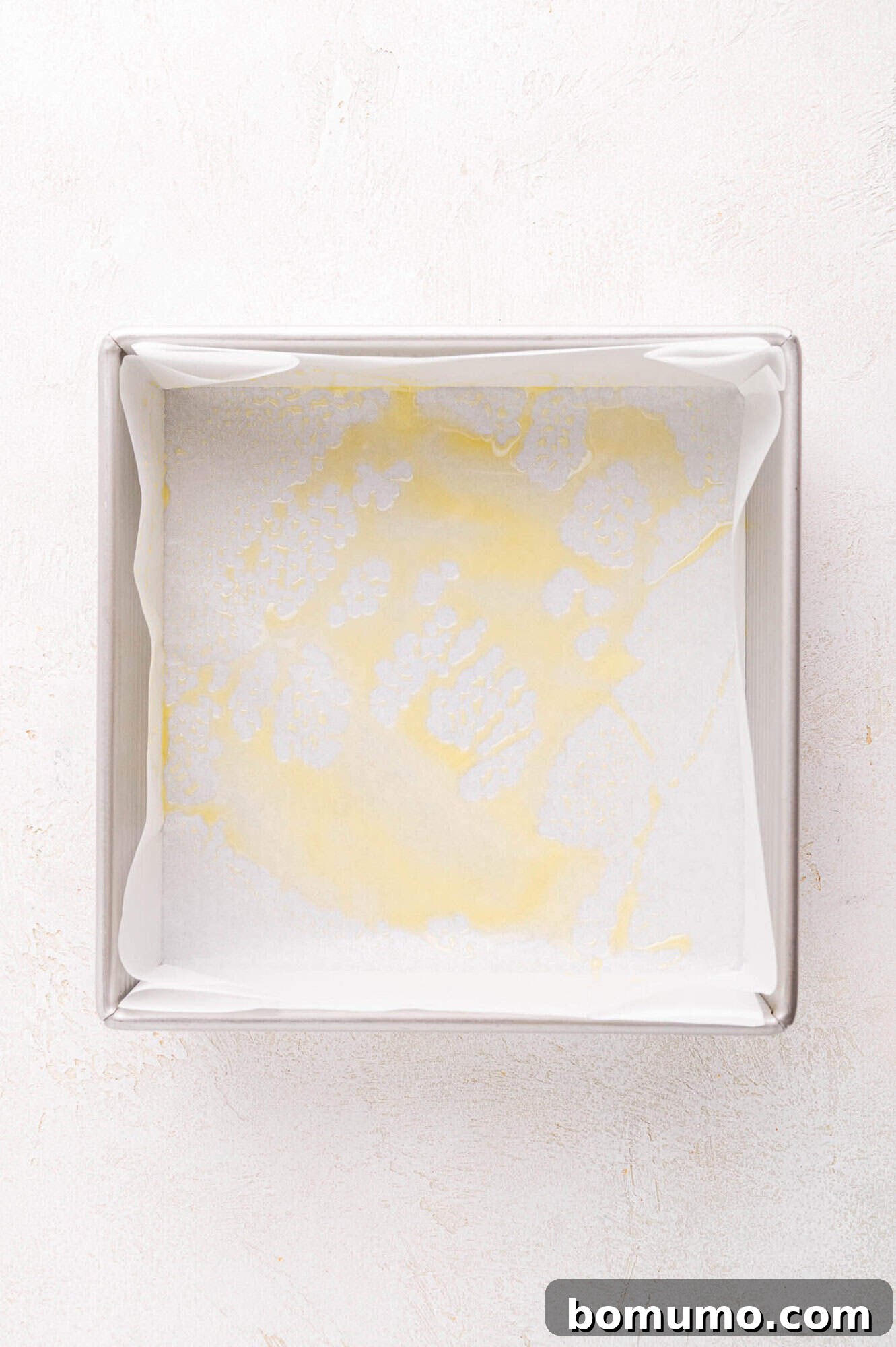 Square baking pan lined with parchment paper.