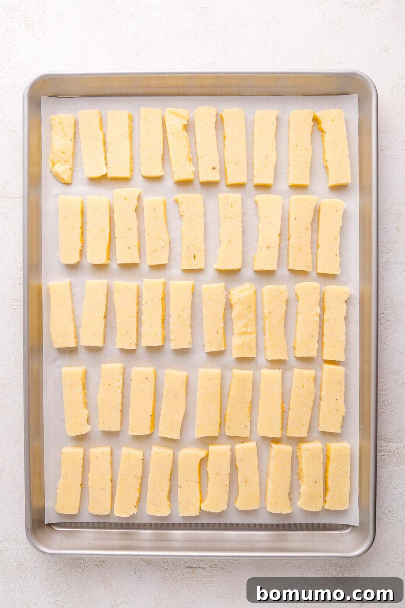 Seasoned polenta fries on a baking sheet.