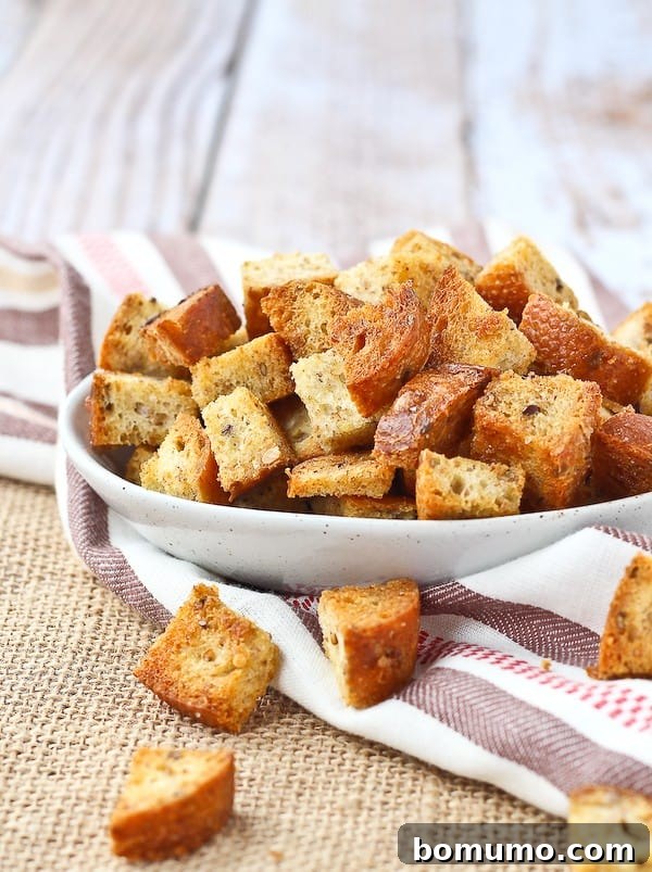 Homemade croutons piled up in a small white bowl, golden brown and perfectly crisp.