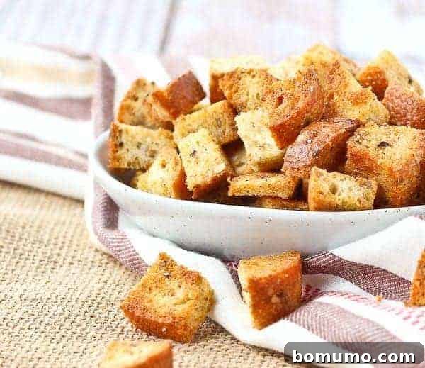 Golden brown homemade croutons spilling out of a small white bowl.