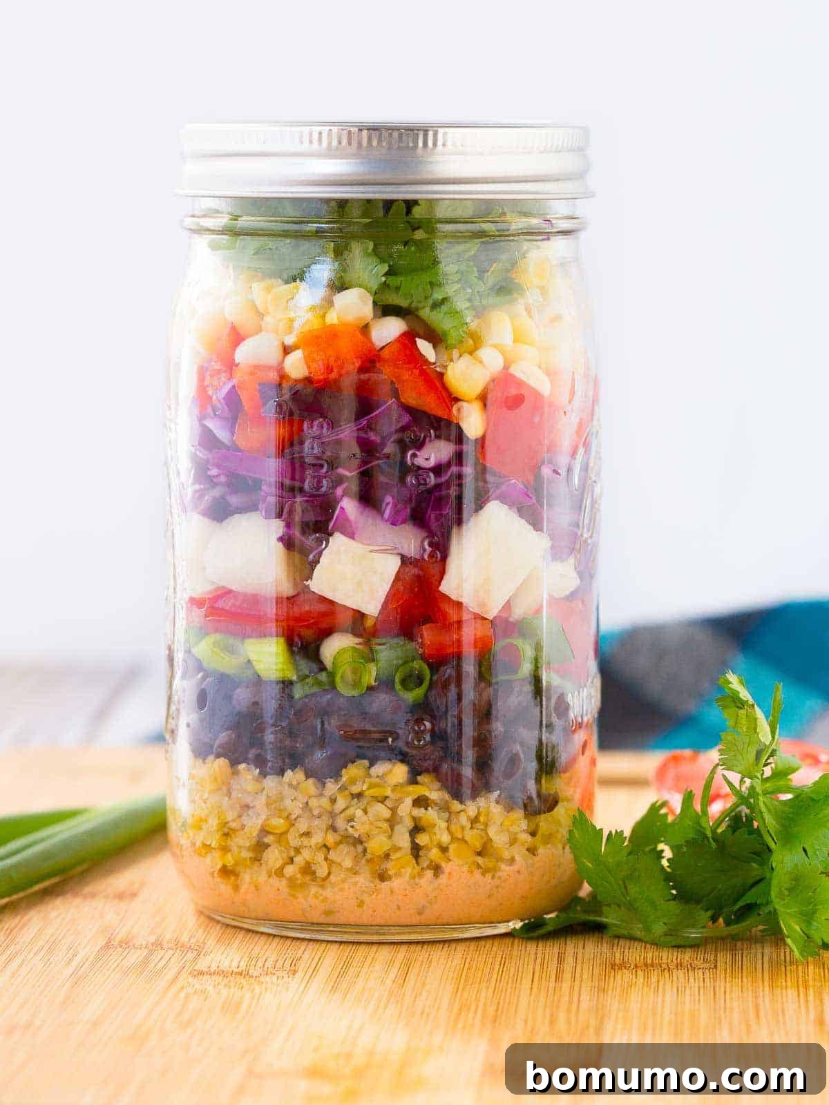 A beautifully layered Southwestern Chopped Salad in a tall mason jar, showcasing vibrant colors and fresh ingredients. Ideal for healthy meal prep.