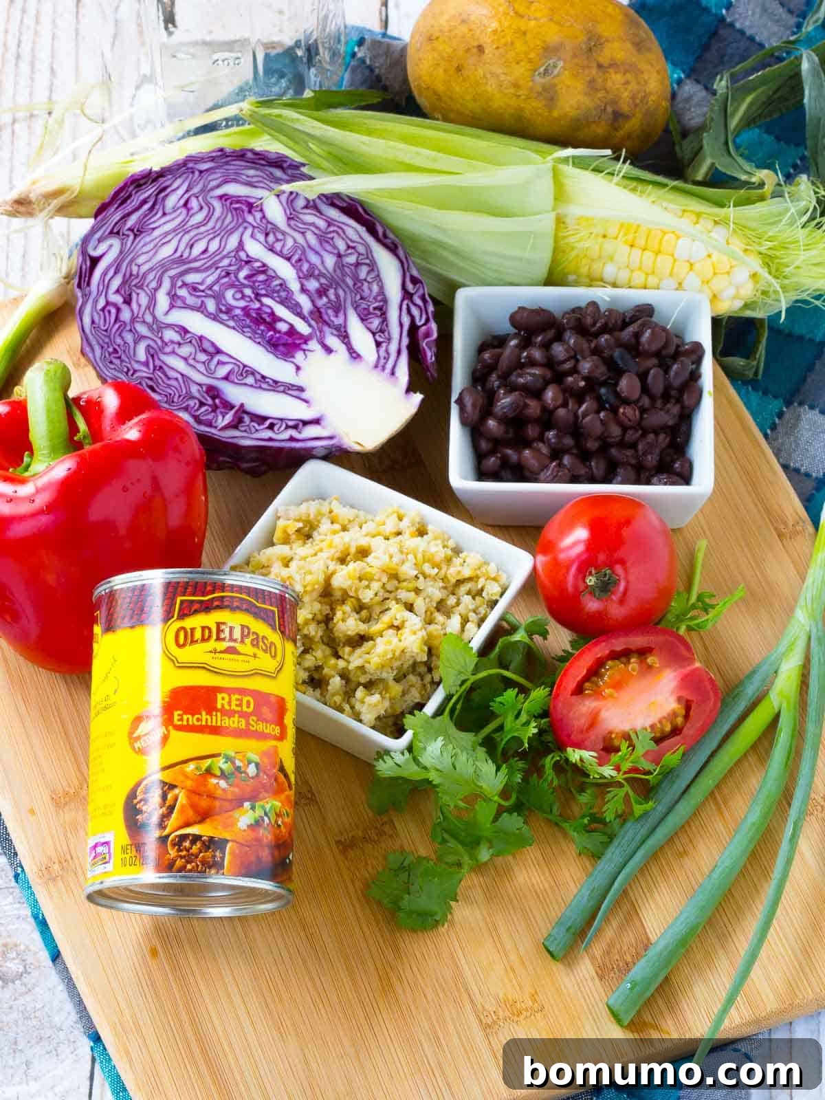 An array of fresh, colorful ingredients for a Southwestern Chopped Salad laid out on a cutting board, including red cabbage, bell peppers, corn, and black beans.