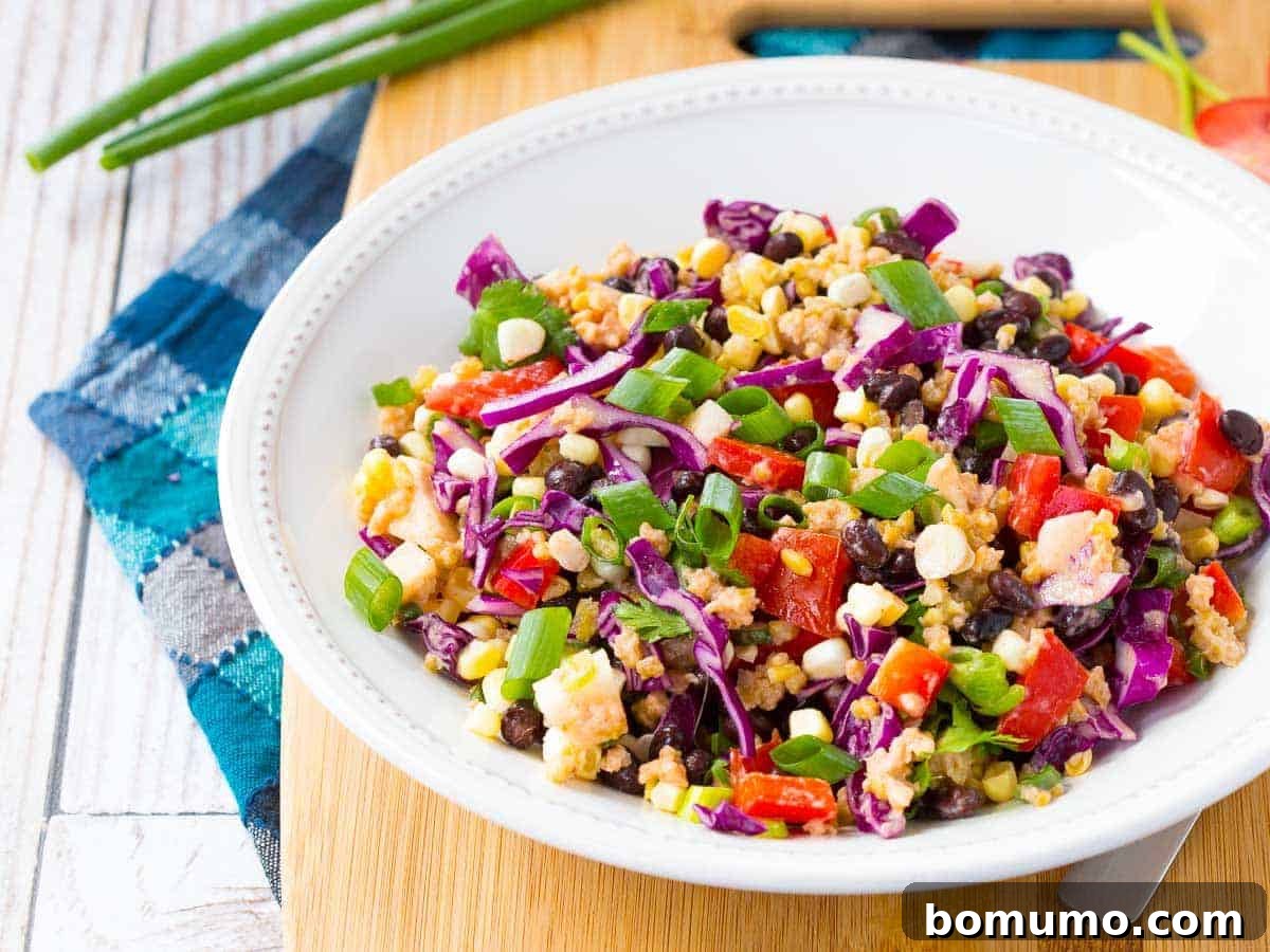 A vibrant Southwestern Chopped Salad, previously layered in a mason jar, now poured into a bowl and ready to be mixed and enjoyed.