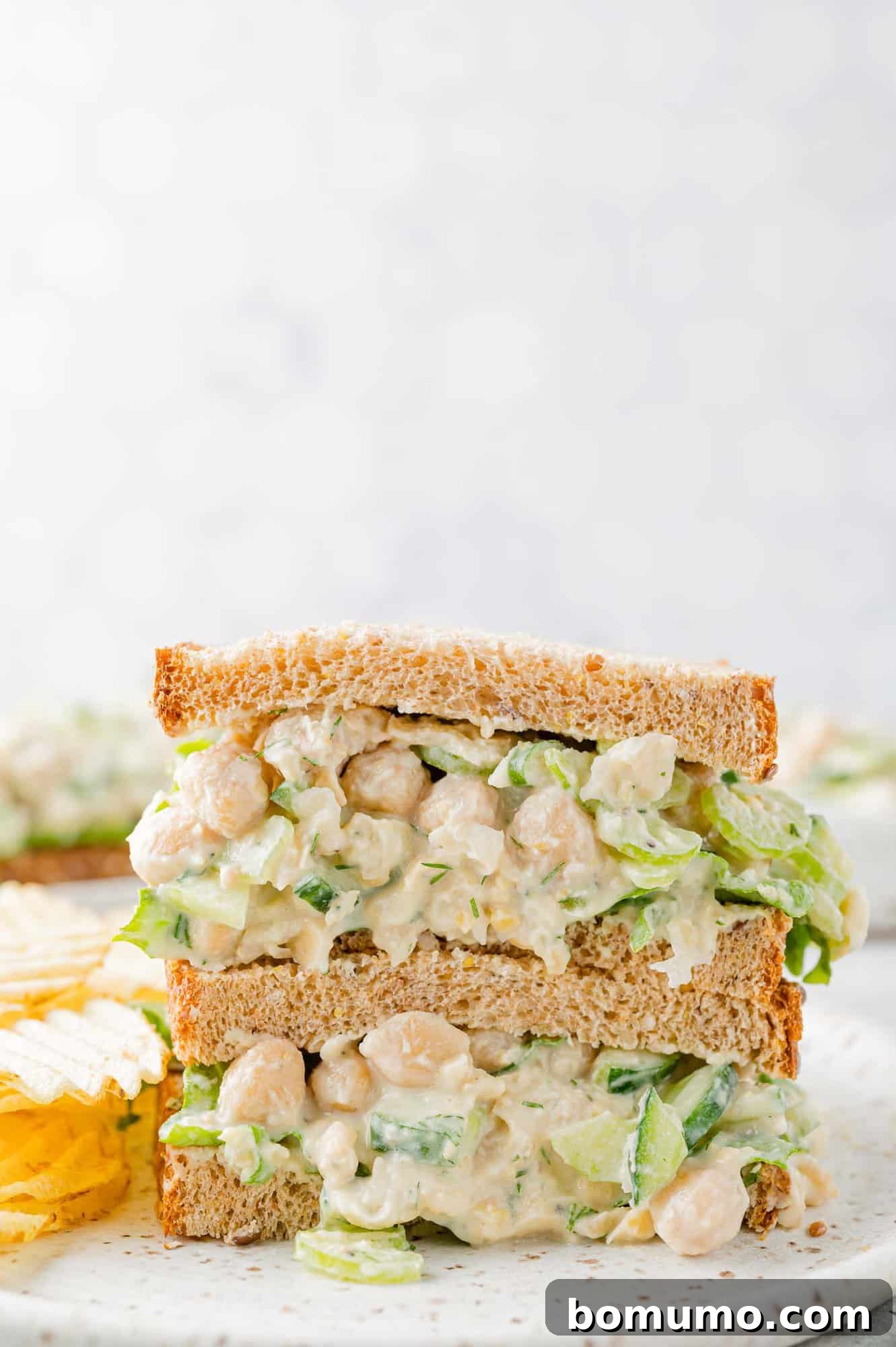 Two perfectly stacked halves of a chickpea salad sandwich, ready to be enjoyed.