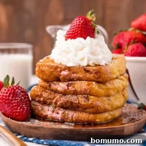 Stack of stuffed french toast, topped with whipped cream and a strawberry.