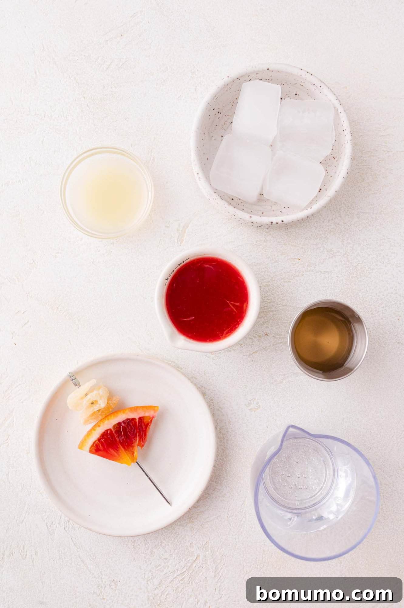 Crimson Sunset Sip 6 An overhead view showcasing various mocktail ingredients neatly arranged: ice cubes, fresh lime juice, vibrant blood orange juice, prepared simple syrup, sparkling water, and garnishes.