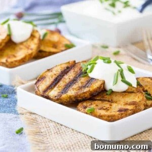 Grilled potatoes on square white plates, garnished with sour cream and chopped chives.
