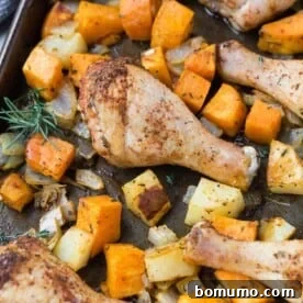 Herb-roasted chicken drumsticks with cubed potatoes and sweet potatoes on a sheet pan, ready to serve.