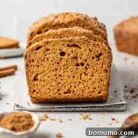 Generous slices of moist pumpkin streusel bread artfully arranged with autumn spices in the background.