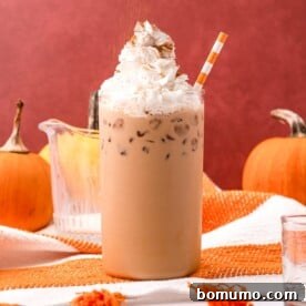 A refreshing Iced Pumpkin Spice Latte, generously topped with whipped cream and a sprinkle of cinnamon, set against a vibrant orange background.