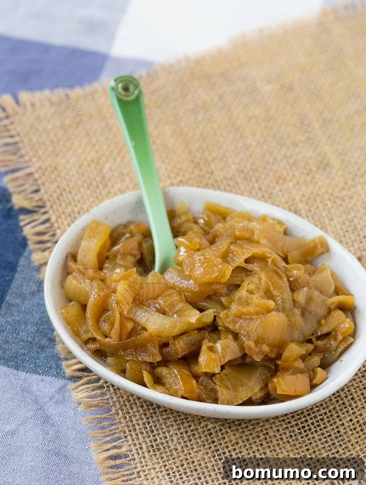 Slow cooker caramelized onions in a small ovel bowl, showcasing their rich, golden-brown hue.