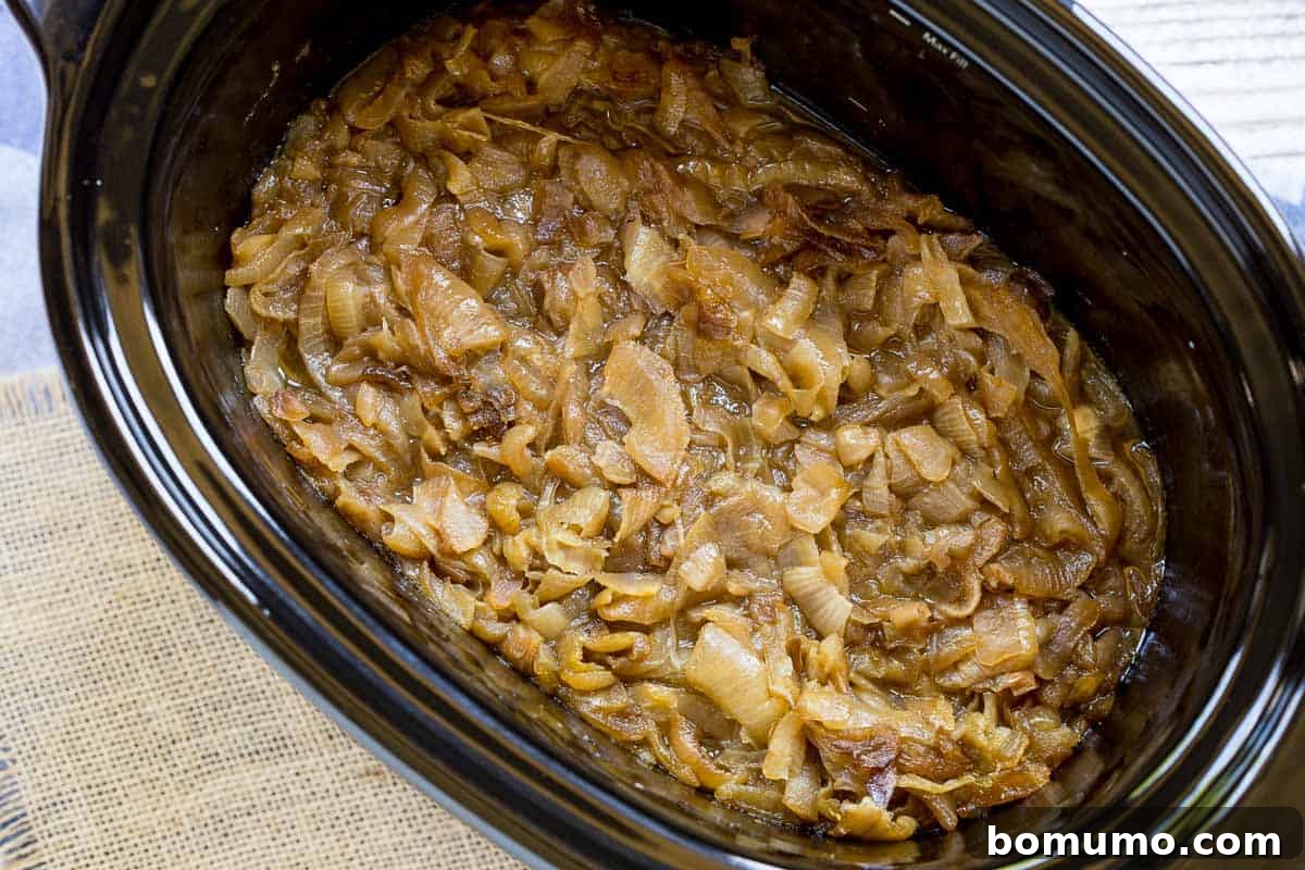 Richly caramelized onions bubbling gently in a slow cooker, showcasing their reduced, jam-like texture.