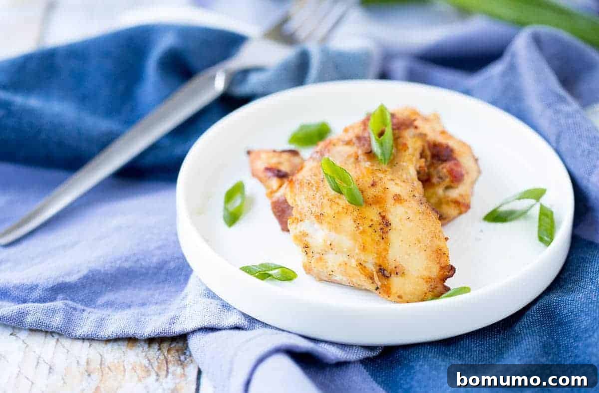 Close-up of grilled chicken thighs served on a small white plate, accompanied by a fork and a vibrant blue napkin, showcasing its appealing golden-brown char.