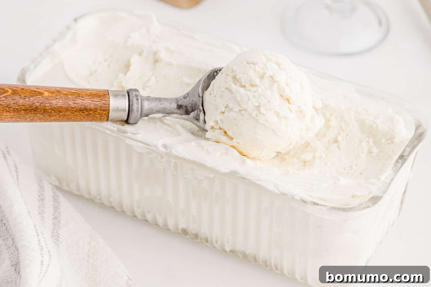 Velvet Vanilla Bliss 6 A large scoop of creamy vanilla ice cream being served from a loaf pan with an ice cream scoop, ready to be enjoyed.