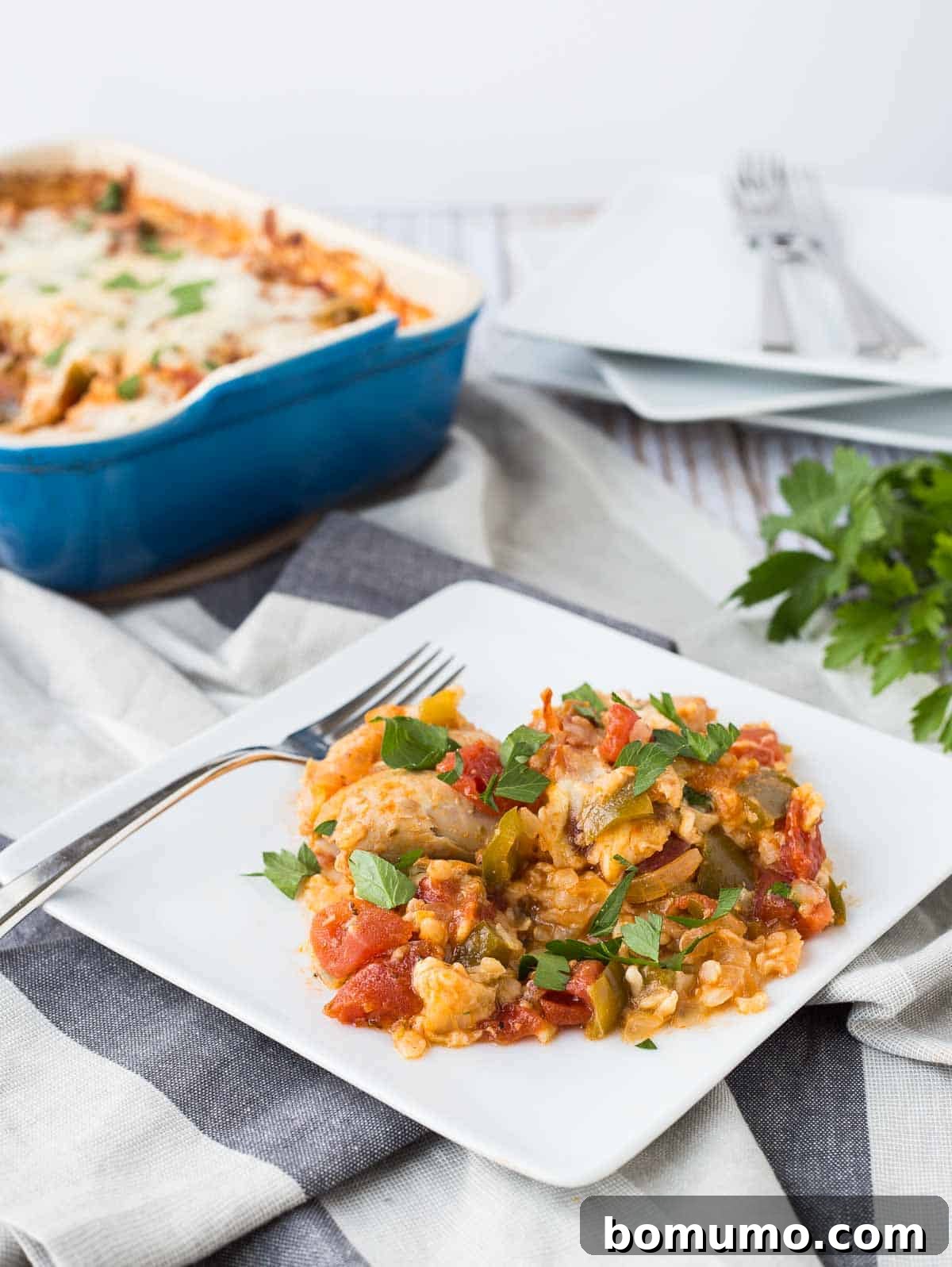 A single serving of the Italian Chicken and Rice Bake presented on a square white plate with a fork, showing the rich texture of chicken, rice, and melted cheese.