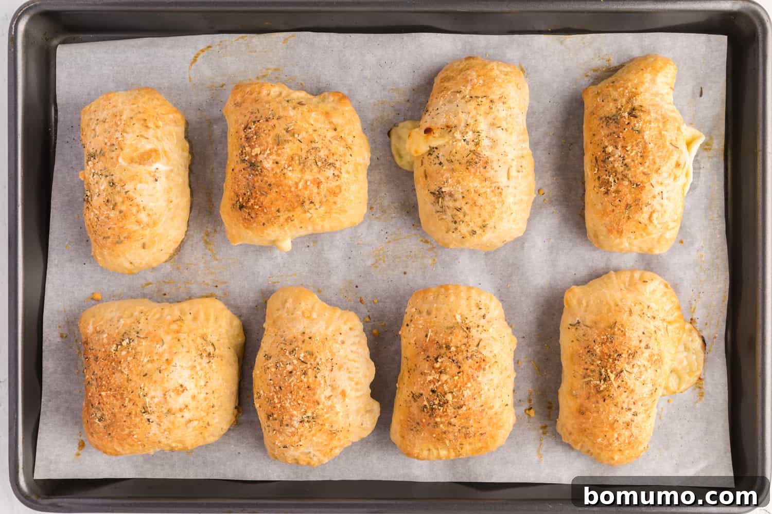 Freshly baked homemade hot pockets, golden brown and perfectly puffed, cooling on a sheet pan.
