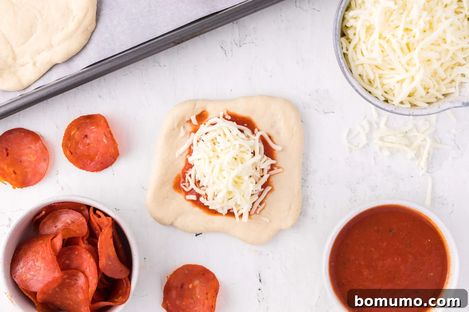 Cheese and sauce added to dough, perfectly centered and ready for toppings.