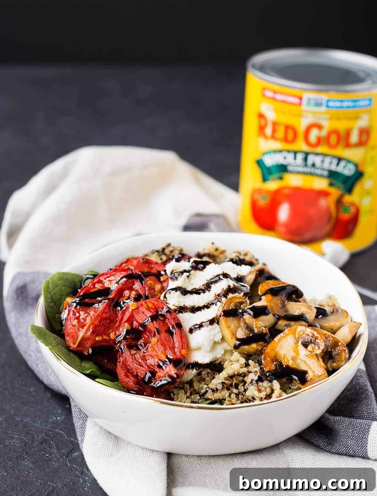 A beautifully arranged quinoa bowl, with a can of Red Gold tomatoes subtly placed in the background, highlighting the quality of the ingredients.